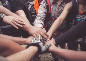 A group of diverse individuals join hands for teamwork in West Java, Indonesia.